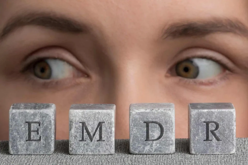 Close-up of a person's eyes looking sideways with four stone blocks spelling 'EMDR' in front.