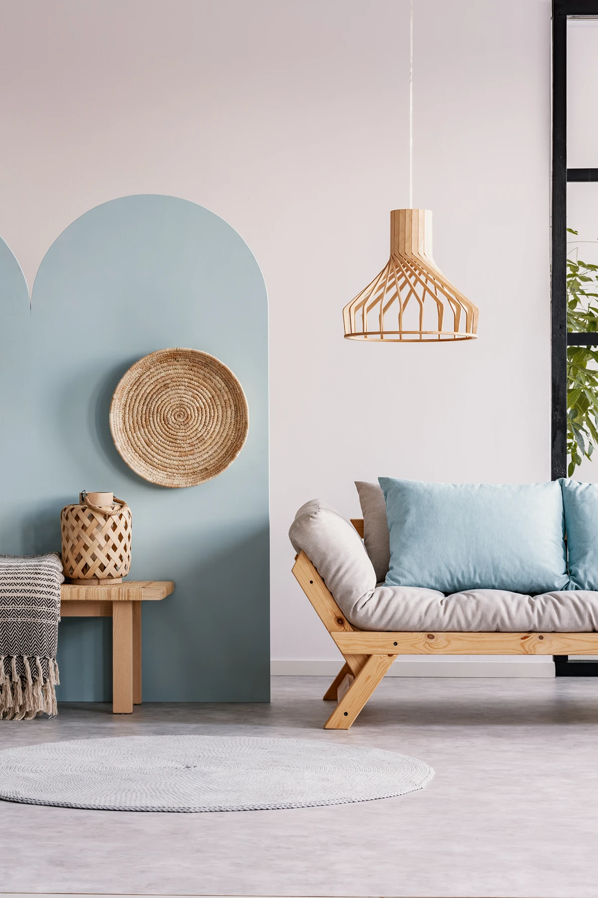 Minimalist living room interior with wooden bench sofa, round rug, and decorative wall elements.