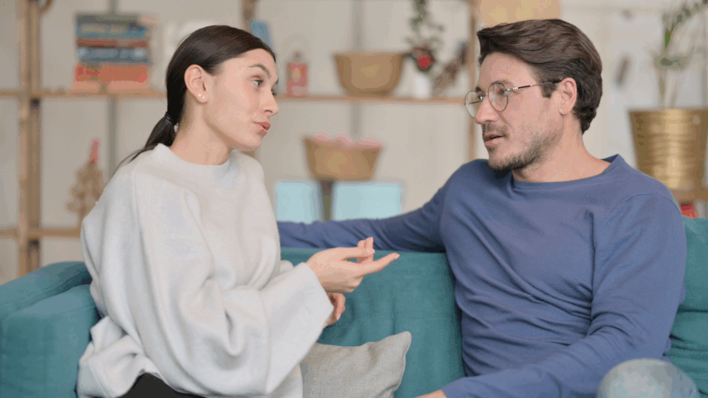 Couple discussing openly on couch; emotional safety doubles chances of staying together over 5 years.