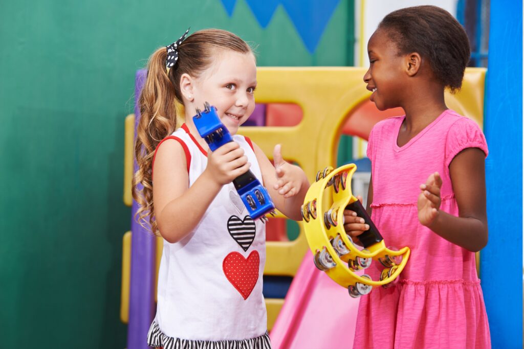 Two children smiling while exploring musical instruments in a supportive music therapy session at Refresh Counselling Calgary